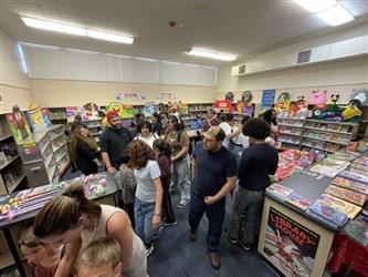 elemenary students in school library walking around looking at books