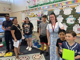 elementary students with parents and teacher in school library
