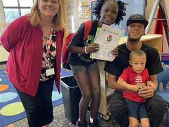 elementary students with parents and teacher in school library
