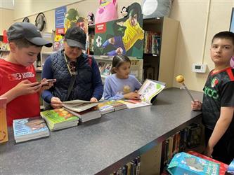 elementary student looks at books on counter in school library