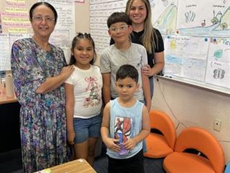 elementary students with parents and teacher in school library