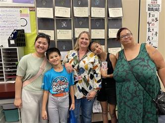 elementary students with parents and teacher in school library